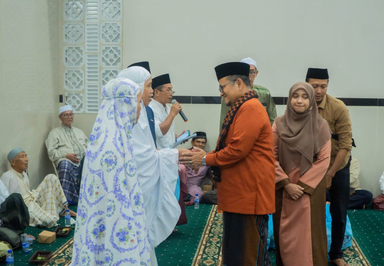 h. maulana didampingi istri saat serahkan paket sembako kepada warga simpang tiga sipin.